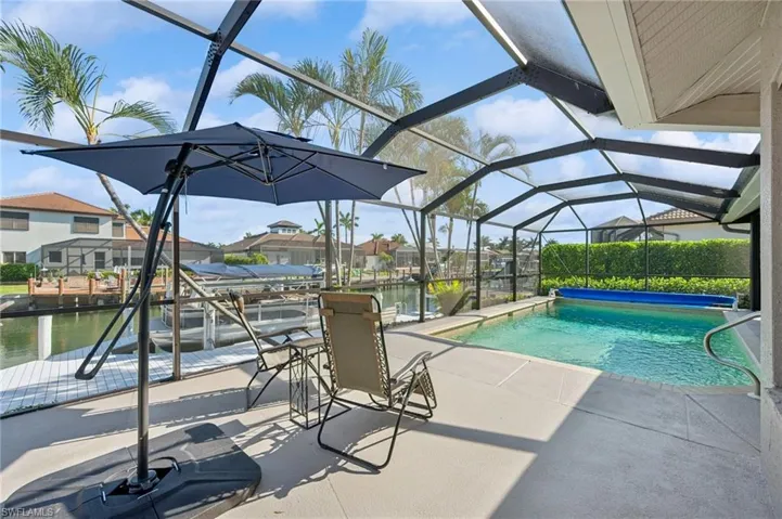 Pool with a patio, a dock, a water view, and glass enclosure