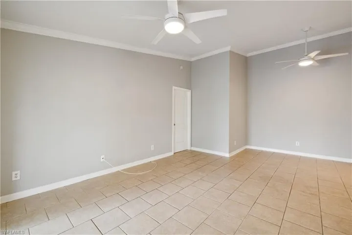 Unfurnished room with crown molding, baseboards, a ceiling fan, and light tile patterned floors