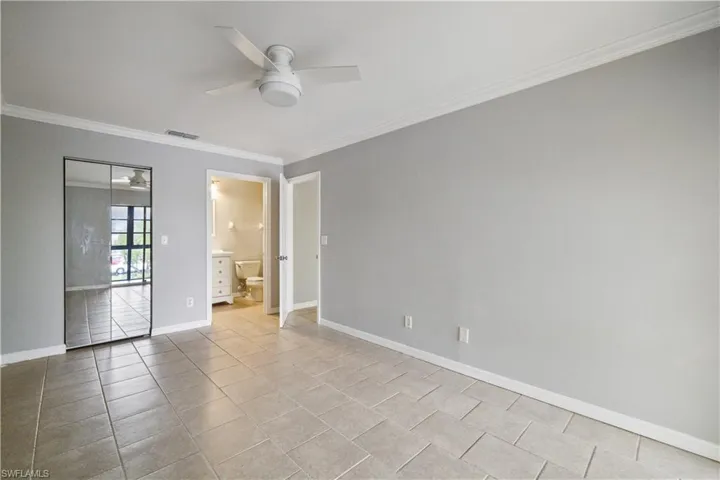Empty room with visible vents, baseboards, ceiling fan, light tile patterned flooring, and ornamental molding