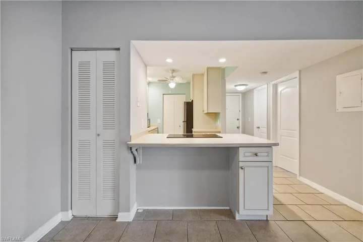 Kitchen featuring a peninsula, light tile patterned flooring, ceiling fan, light countertops, and baseboards