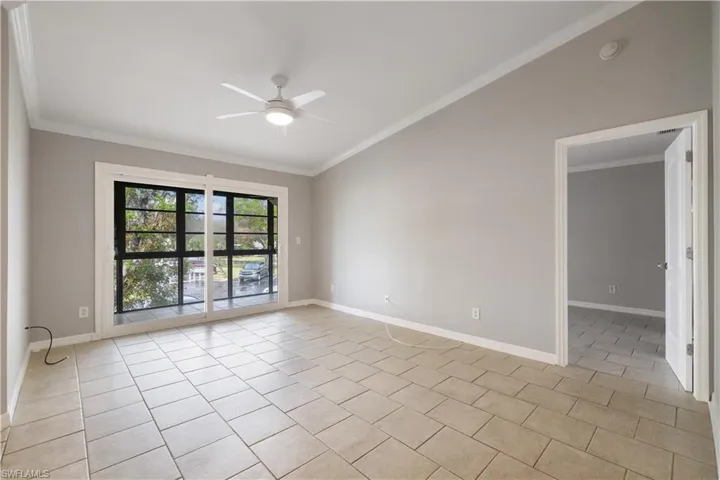 Unfurnished room featuring crown molding, light tile patterned floors, baseboards, and ceiling fan