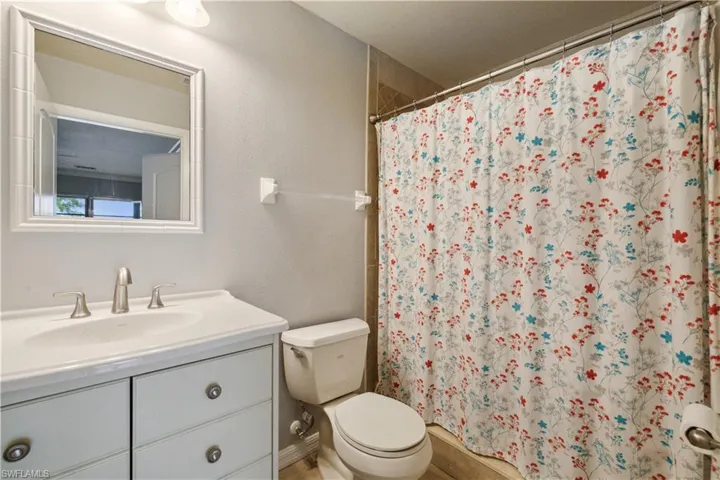 Bathroom featuring curtained shower, vanity, and toilet