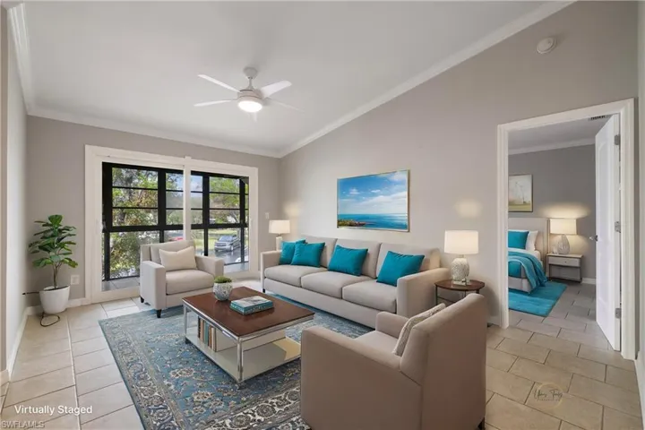 Living room featuring a ceiling fan, lofted ceiling, ornamental molding, and baseboards