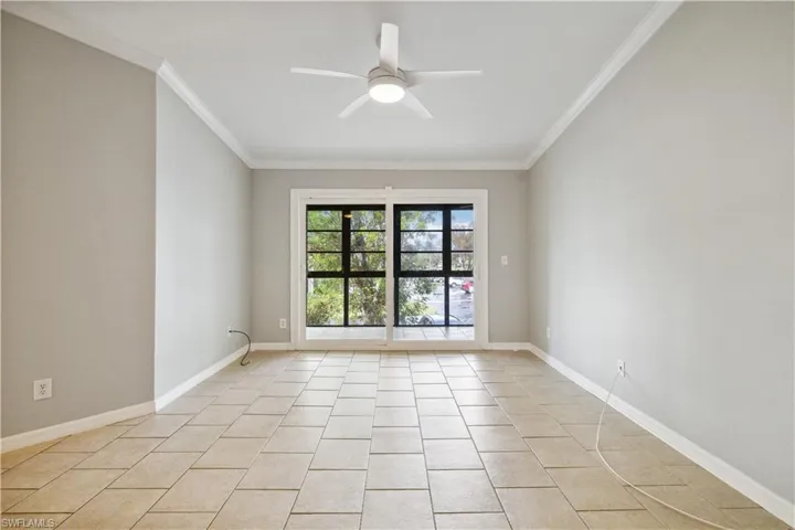 Empty room with a ceiling fan, ornamental molding, light tile patterned floors, and baseboards