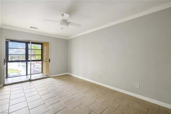 Empty room featuring tile patterned floors, crown molding, visible vents, baseboards, and ceiling fan