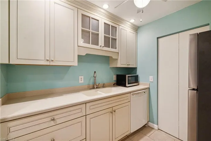 Kitchen featuring light tile patterned floors, a ceiling fan, a sink, light countertops, and appliances with stainless steel finishes