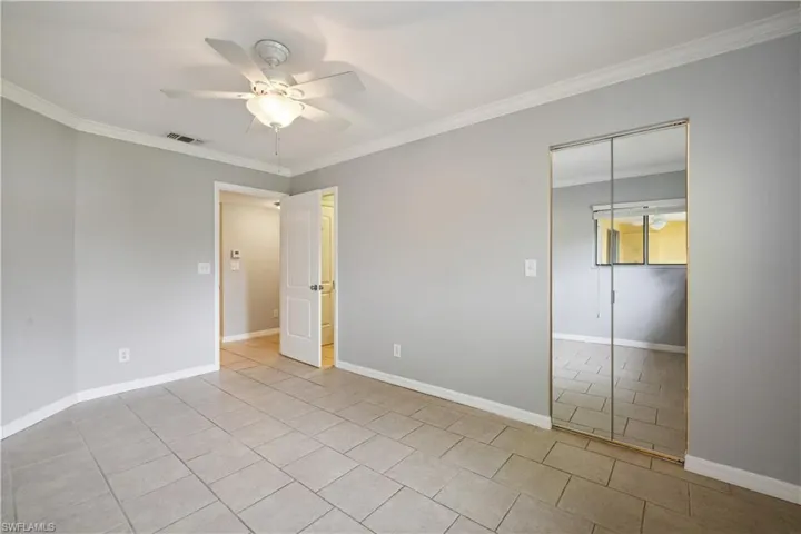 Unfurnished bedroom featuring tile patterned flooring, ornamental molding, baseboards, and visible vents