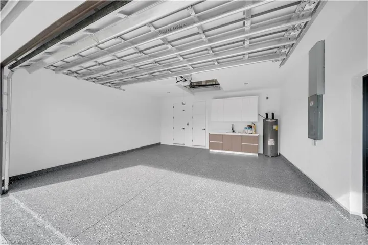 Misc room with a garage, electric panel, water heater, and speckled floor