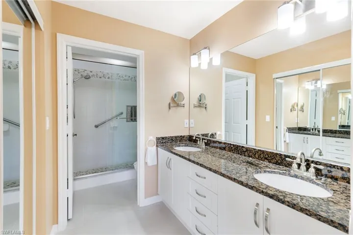 Remodeled primary bath with granite vanity and glass-enclosed walk-in shower