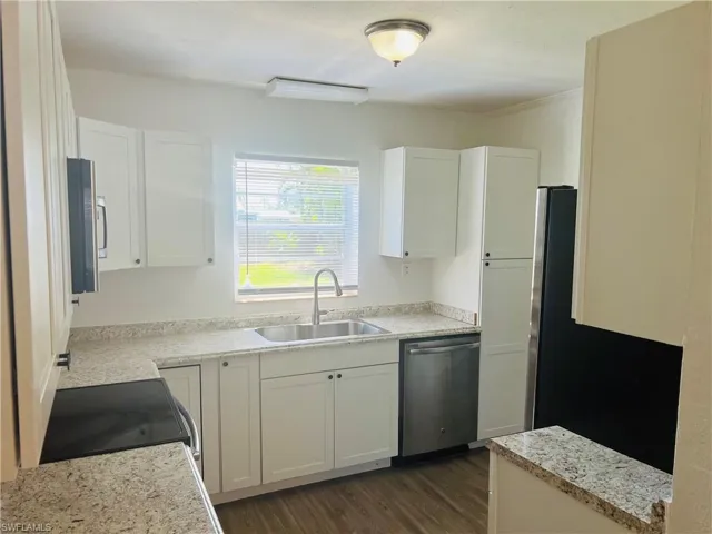 Kitchen featuring white cabinetry, sink, dark hardwood / wood-style floors, and dishwasher