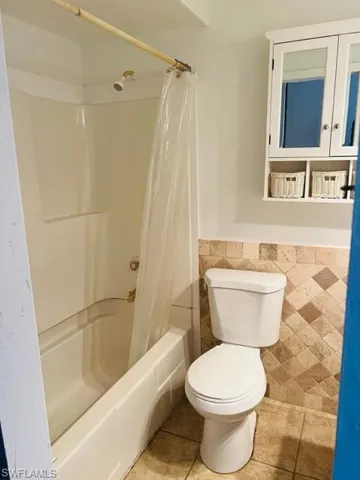 Bathroom featuring tile floors, shower / tub combo, and toilet