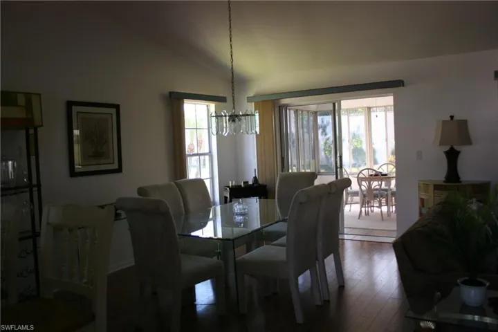 Dining room featuring vaulted ceiling, dark wood-type flooring, and a chandelier