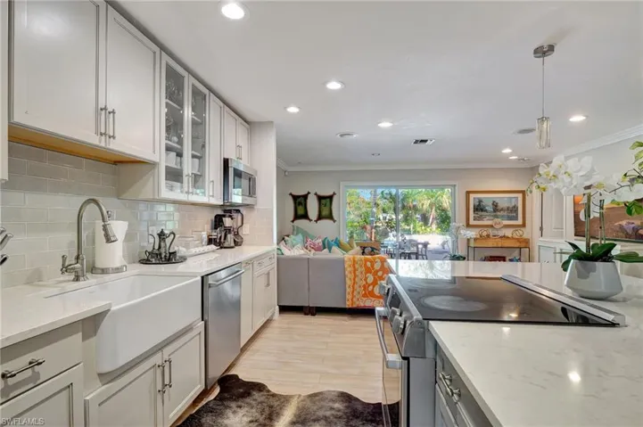Kitchen featuring stainless steel appliances, a sink, crown molding, tasteful backsplash, and light stone counters