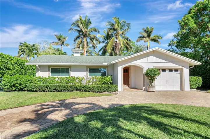 Ranch-style home with a front lawn, an attached garage, driveway, and stucco siding