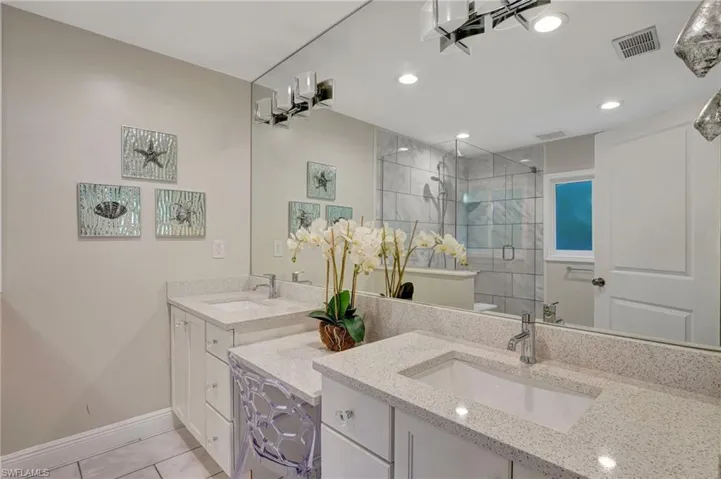 Main bathroom with a stall shower, baseboards, tile patterned floors, two vanities, and recessed lighting