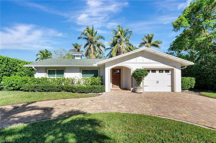 Ranch-style house with a garage, decorative driveway, and a front yard
