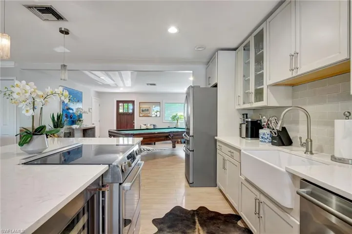 Kitchen featuring stainless steel appliances, light wood-style flooring, a sink, and tasteful backsplash