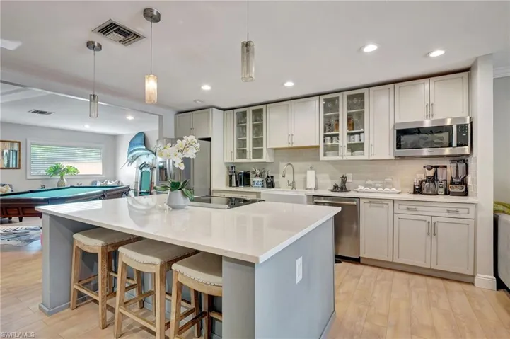 Kitchen featuring stainless steel appliances, a sink, a breakfast bar area, light wood-style flooring, and tasteful backsplash
