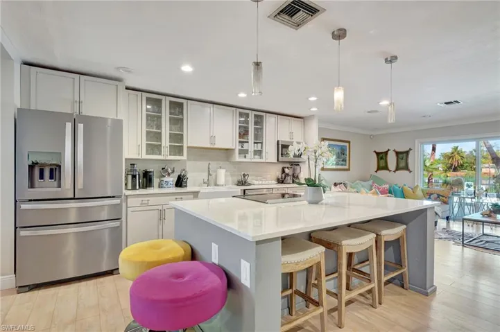 Kitchen with appliances with stainless steel finishes, a sink, ornamental molding, light wood-style flooring, and a center island