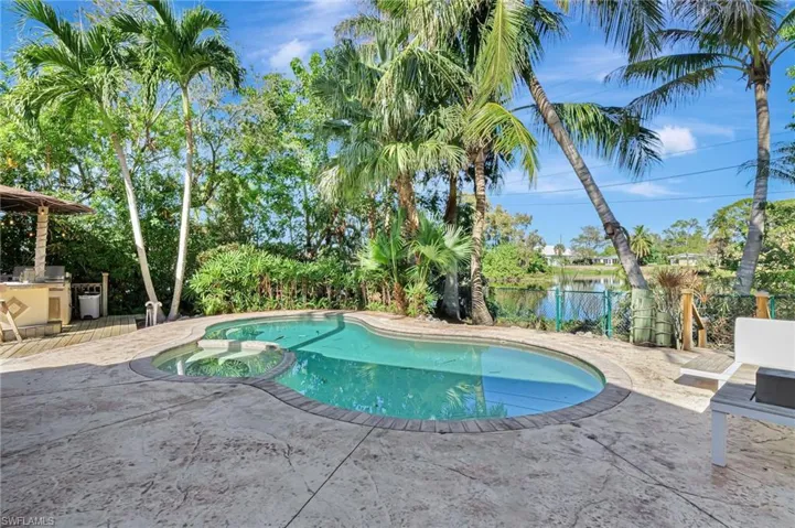 View of swimming pool with fence, a patio, a pool with connected hot tub, and an outdoor kitchen