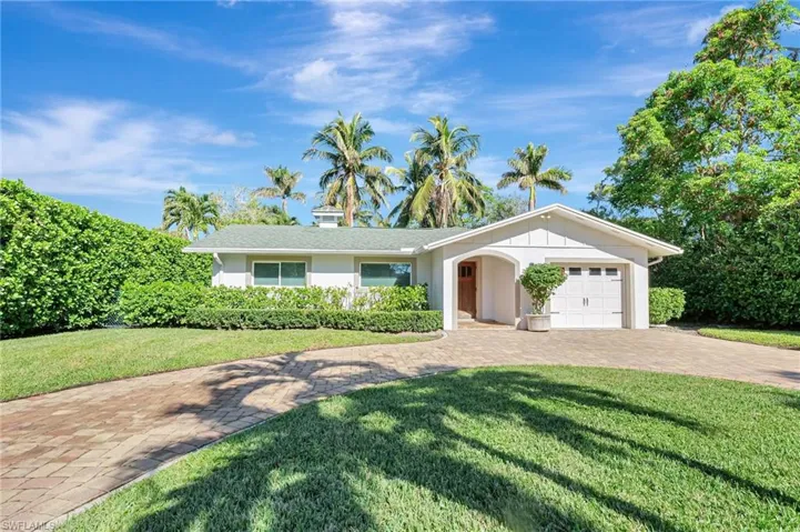 Single story home featuring a garage, a front yard, and decorative driveway