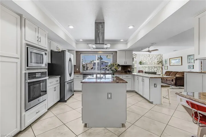 Kitchen with a peninsula, a center island, ornamental molding, appliances with stainless steel finishes, and open floor plan
