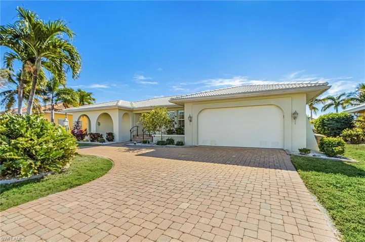 View of front of home with stucco siding, decorative driveway, and an attached garage