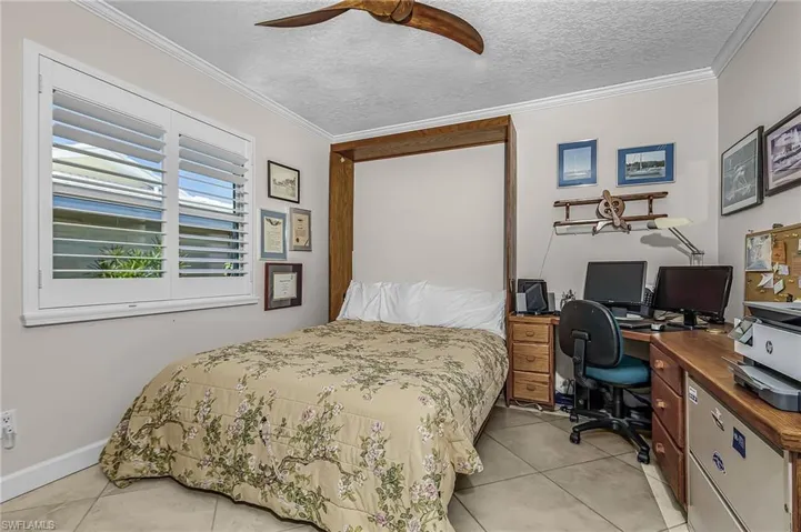 Bedroom with a textured ceiling, crown molding, a desk, ceiling fan, and light tile patterned flooring