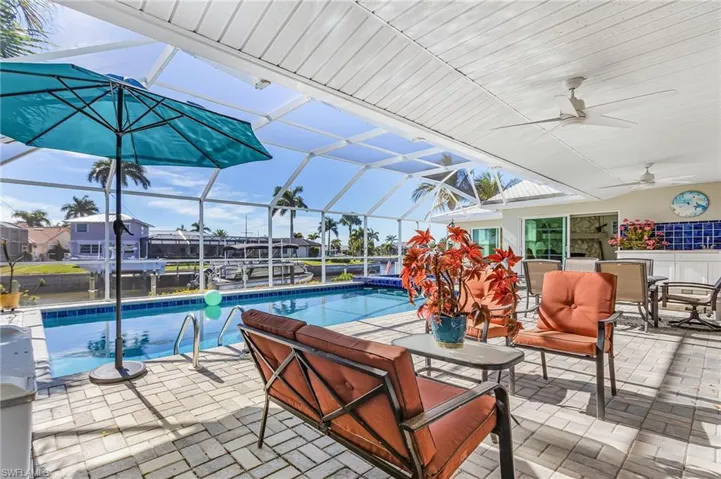 Outdoor pool featuring a sunroom, a patio, glass enclosure, and outdoor dining area