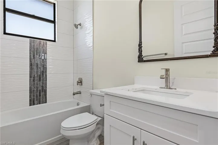 Full bathroom featuring vanity, tiled shower / bath combo, and toilet