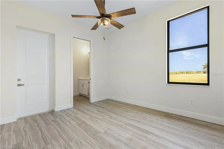 Unfurnished bedroom with light hardwood / wood-style flooring, ensuite bath, and ceiling fan