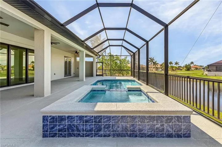 View of swimming pool featuring a patio, an in ground hot tub, ceiling fan, and glass enclosure