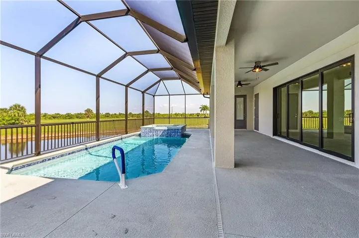 View of swimming pool featuring an in ground hot tub, a patio, glass enclosure, and ceiling fan