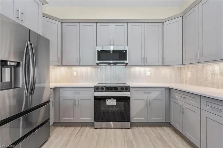 Kitchen featuring appliances with stainless steel finishes, backsplash, and gray cabinetry