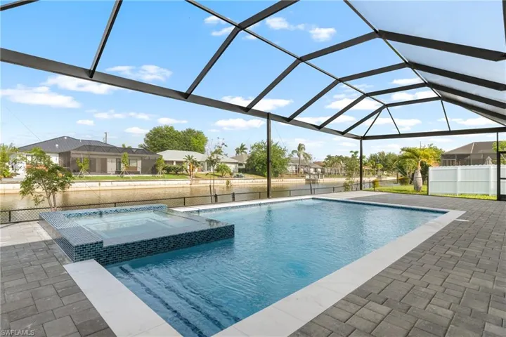 Screened outdoor living area featuring a rectangular pool with integrated spa