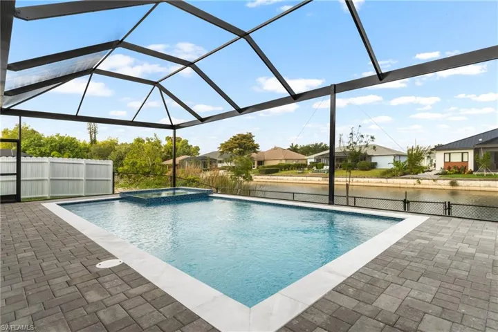 Screened outdoor living area featuring a rectangular pool with an integrated spa