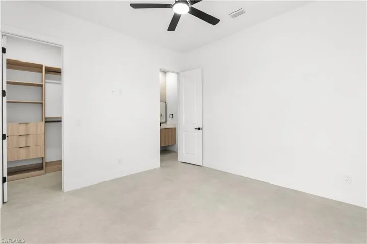 Spacious room featuring light-toned flooring, a ceiling fan, and crisp white walls