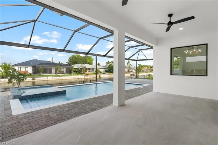 Expansive screened lanai featuring a swimming pool, integrated spa with mosaic tile accents, and a canal frontage