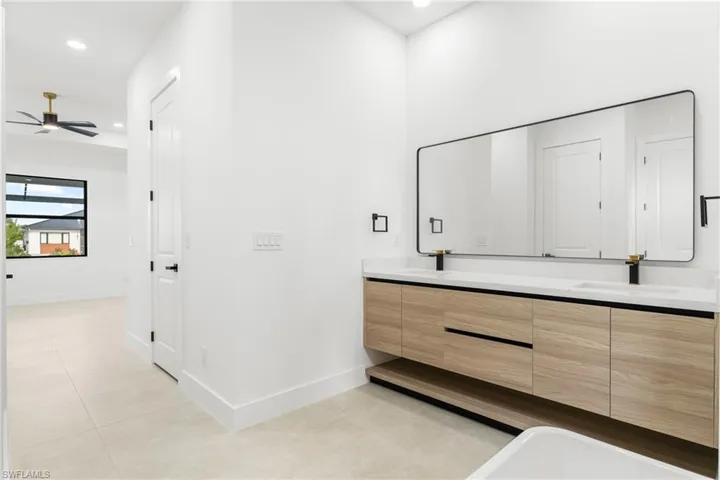 Dual vanity with wood-finish cabinetry, white countertop, and rectangular black-framed mirror