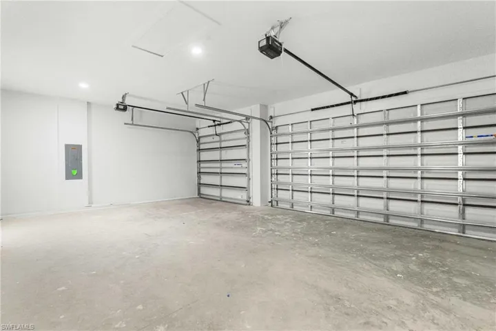 Spacious garage with concrete flooring, two overhead garage doors, and recessed lighting
