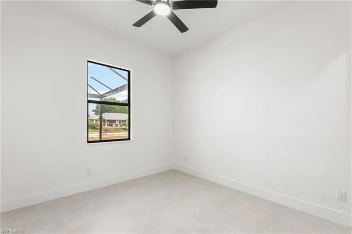 Bright interior space featuring a black-framed window, a ceiling fan with light, light-toned flooring, white walls, and white baseboards