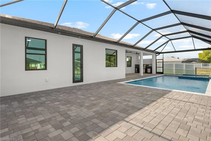 Screened lanai featuring a swimming pool, integrated spa, and an outdoor kitchen area