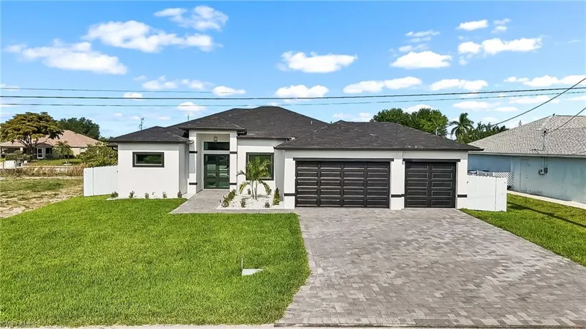 Contemporary white stucco exterior with a dark roof, paver driveway, and a two-car garage