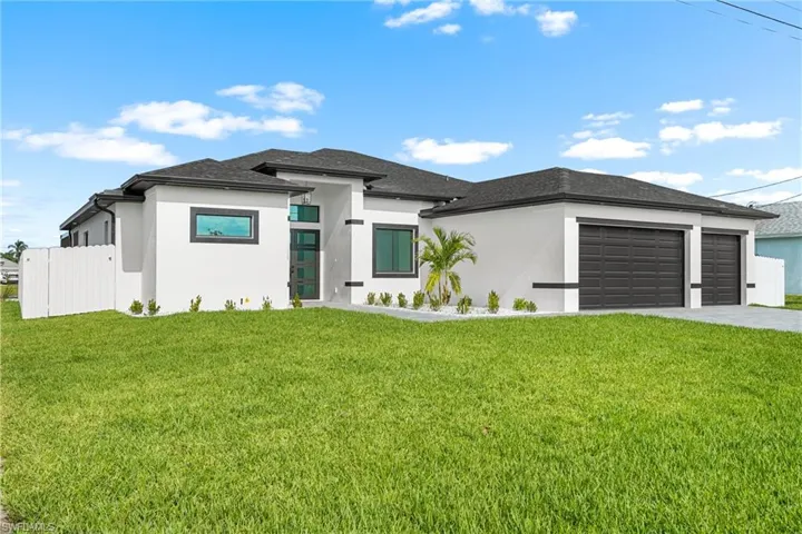 Contemporary exterior featuring a white stucco facade, dark trim accents, a two-car garage, and a lush green lawn