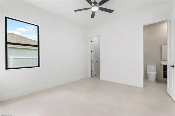 Bright interior space featuring light-toned tile flooring, a contemporary ceiling fan with integrated lighting, and a large window with black framing
