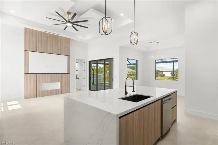 Expansive open-concept space featuring a large kitchen island with a waterfall countertop and integrated sink