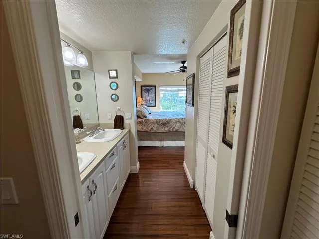 Dual vanity with integrated sinks and white cabinetry, complemented by dark wood-finish flooring