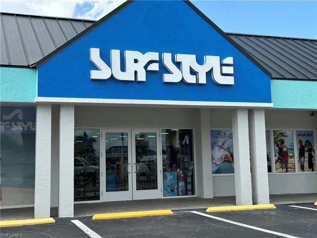 Commercial storefront featuring prominent signage, a metal roof, and a vibrant blue stucco facade