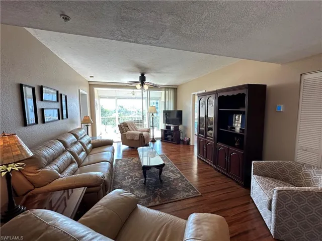 Spacious living area featuring wood-finish flooring, a ceiling fan, and access to an outdoor patio with white railings