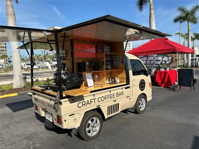 Compact mobile coffee bar featuring a beige exterior, wood-finish shelving, and a prominent espresso machine